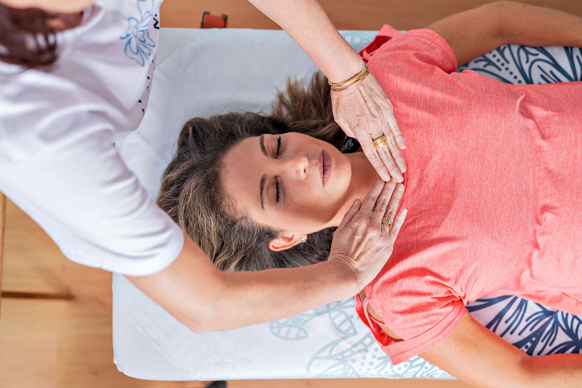 Woman receiving reiki therapy with hands near her throat in a calm setting