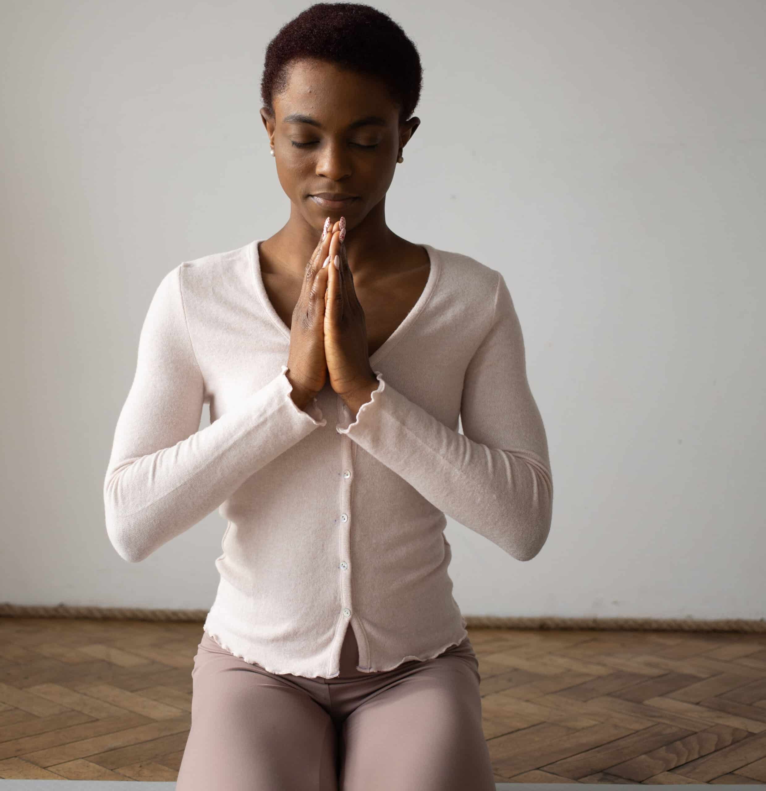 Woman meditating in prayer pose on hardwood floor