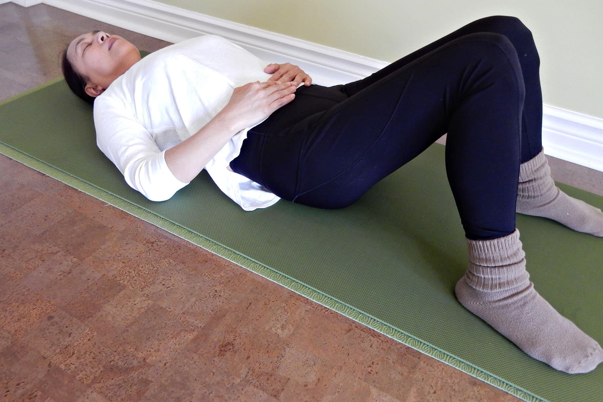 Person practicing relaxation exercises on a yoga mat indoors