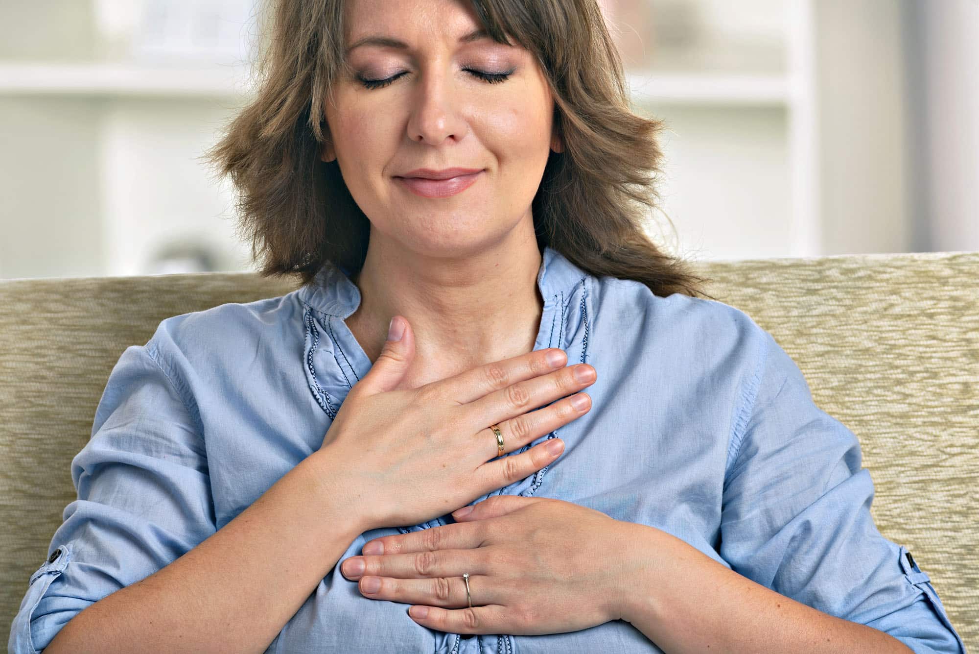 Woman practising mindfulness meditation with hands on heart