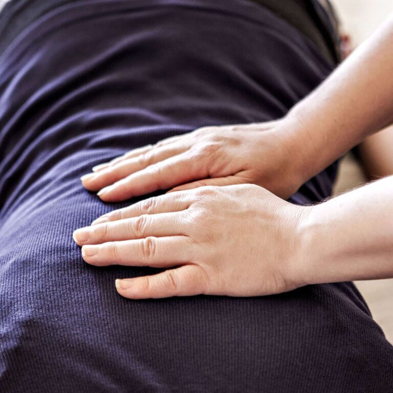 Hands performing Reiki therapy on a person's back