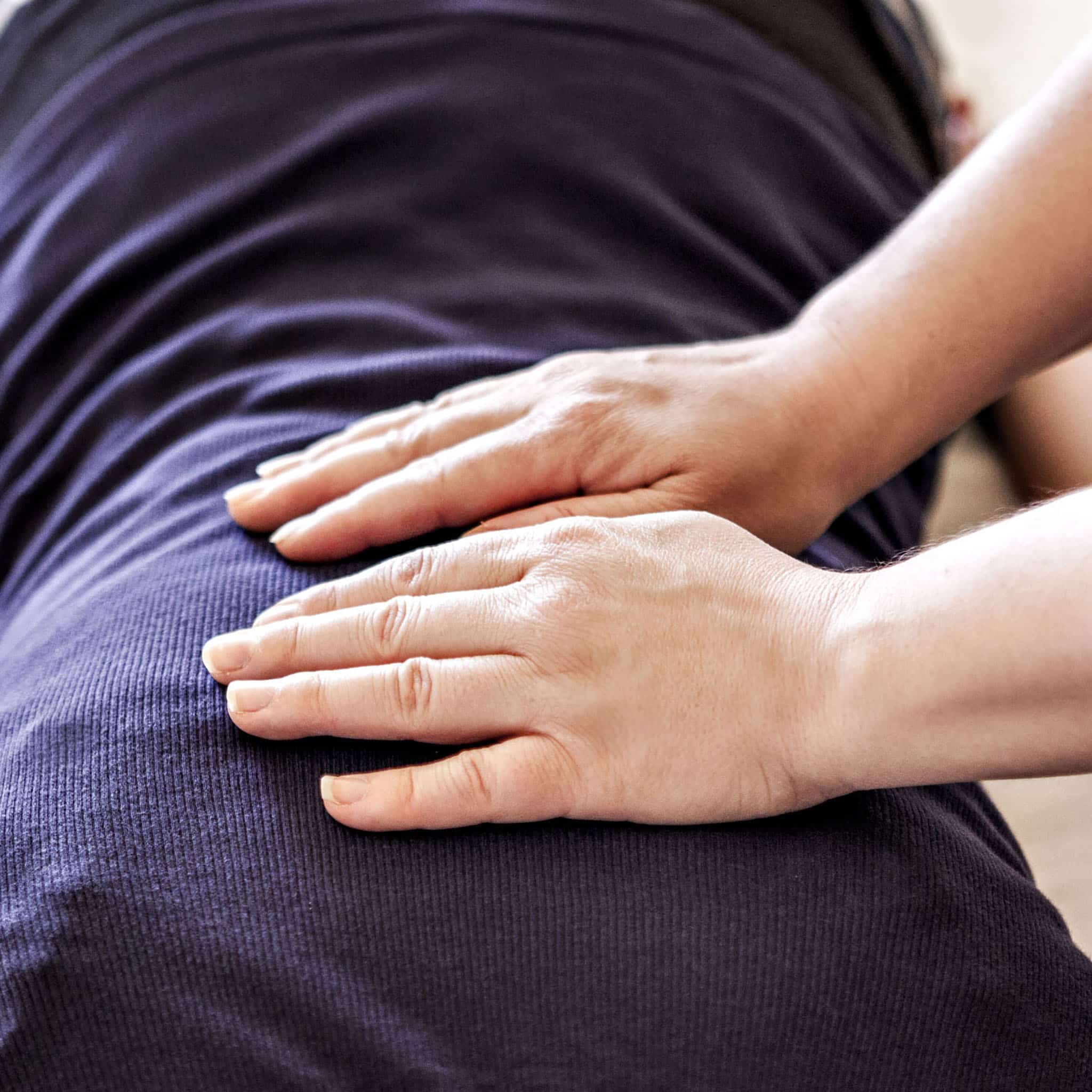 Hands performing Reiki therapy on a person's back