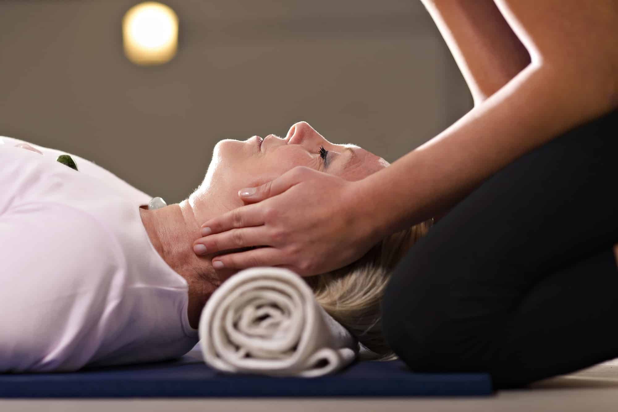 Woman receives craniosacral therapy with rolled towel support