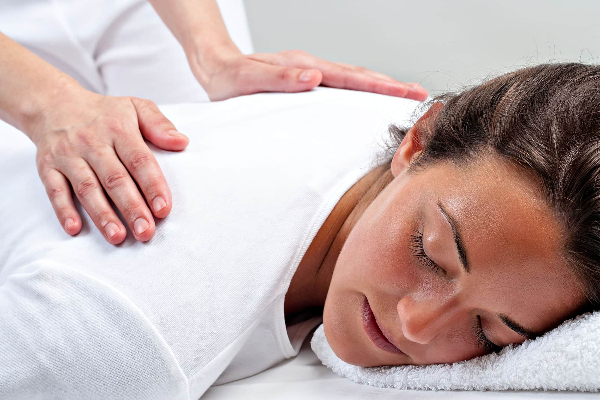 Woman receiving a relaxing back massage on white towel