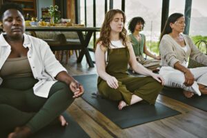 Diverse group meditating in a serene indoor setting with mountains view